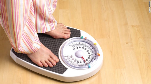 Person weighing themselves on scale